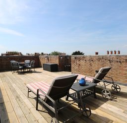 A roof terrace with deck chairs and a dining table at Skylark in Southwold