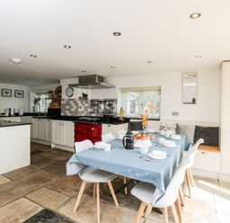 A kitchen and dining area with a table set for breakfast and kitchen cabinets at 2 Dewars Farm Cottages in Middleton Stoney