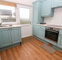 A kitchen with blue cabinets wooden floor and a stainless steel oven at Ramblers Rest in St Just