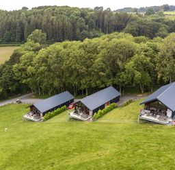 A view of three houses situated on grass near trees at Barcud Coch - Red Kite in Garthmyl