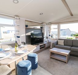 A living room with a dining table set with plates and glasses a television on a stand a sofa and a coffee table at 17 Summer Meadows in Ashington