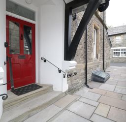 An entrance with a red door and steps leading to a stone-paved walkway beside a stone building at Belle Vue in Hay on Wye Herefordshire