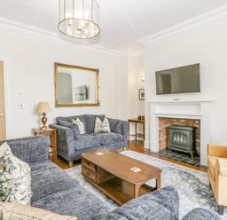 A living room with gray sofas a wooden coffee table a fireplace with a mounted TV and an armchair at Belle Vue in Hay on Wye Herefordshire