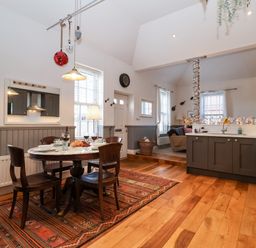 A kitchen and dining area with a round table, four chairs, a rug, and kitchen cabinets at Ebenezer Chapel in Knodishall nr Saxmundham