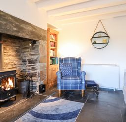 A living room with a fireplace and armchair at Ael Y Bryn in Ffestiniog