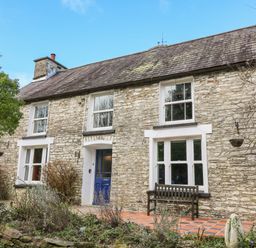 Stone house with blue door wooden bench and tiled porch at Cringoed House Llanarth near Aberaeron