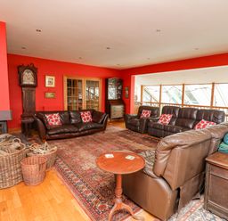 A living room with leather sofas and a fireplace with baskets of firewood at Cringoed House Llanarth near Aberaeron