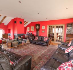 A living room with red walls brown leather sofas a fireplace and wooden furniture at Cringoed House Llanarth near Aberaeron