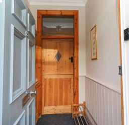 A hallway with a front door and internal door at Rose House Alnmouth