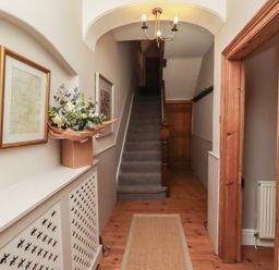 A hallway with a staircase and flower arrangement at Rose House Alnmouth