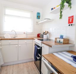 A kitchen with a sink oven countertop and small table with fruit bowl at Dollys Lookout in Kessingland