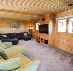 A living room with green and black sofas a wall mounted tv wooden walls and ceiling at iLodge Ultra Kenwick near Louth