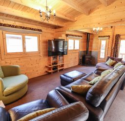 A living room with leather sofas a green armchair a wood burning stove and a mounted television at iLodge 73 Kenwick near Louth