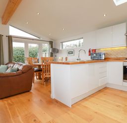 A kitchen and dining area with a brown couch wooden dining table chairs and white cabinets at 10 Faraway Fields in Dobwalls