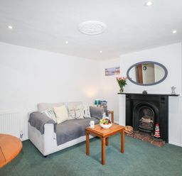 A living room with a sofa coffee table fireplace and television at Angel Cottage in Weymouth