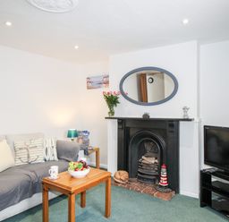 A living room with a sofa coffee table fireplace and television at Angel Cottage in Weymouth