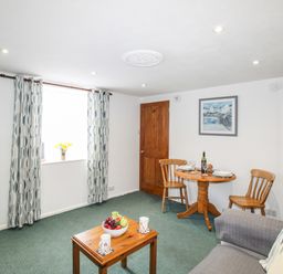 A living room with wooden door table chairs and patterned curtains at Angel Cottage in Weymouth