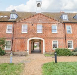 A brick building with multiple windows and a central archway leading through at Feathers Blythburgh in Reydon