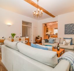 A living room with sofas dining table set with wine glasses and a kitchen in the background at Feathers Blythburgh in Reydon