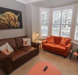 A living room with two sofas a coffee table and a painting of a bull at Snowflake Cottage in Windermere