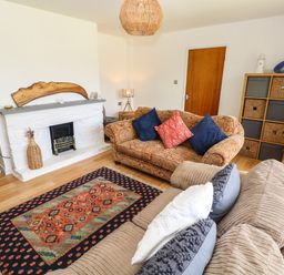 A living room with two sofas a fireplace a patterned rug and a storage unit at Glynderi in Cilgerran