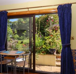 A dining room with a table and chairs overlooking a garden at Turnpike Lodge in Brixham