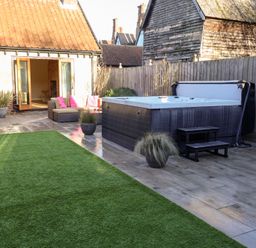 A garden with a hot tub and seating area at The Stables at Hall Barn Wattisfield near Walsham-Le-Willows