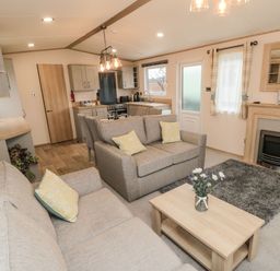 A living room and kitchen area with sofas dining table coffee table and fireplace at 20 Wolds View in East Heslerton near West Heslerton