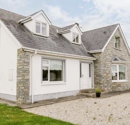 A detached house with mixed stone and white walls and a gravel driveway at The Glen in Carndonagh County Donegal