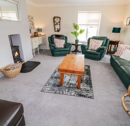 A living room with green leather sofa and chairs wooden coffee table and fireplace at The Glen in Carndonagh County Donegal