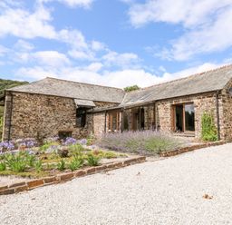 A stone house with slate roof surrounded by flower beds and gravel driveway at Birchenhayes in St Dominick