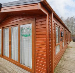A wooden cabin with glass doors and deck outside at Pegasus in Felmoor Park