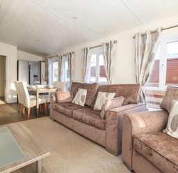 A living area with brown sofas and patterned curtains next to a dining table with chairs and a refrigerator at Canis in Felmoor Park