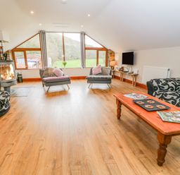 A living room with wood flooring two armchairs patterned sofa coffee table and fireplace at Monkleigh Mill in Monkleigh near Bideford