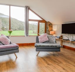 A living room with two gray armchairs and a wall-mounted television at Monkleigh Mill in Monkleigh near Bideford