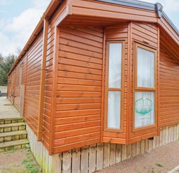 Exterior view of a wooden cabin with windows and a small wooden deck at Draco in Felmoor Park