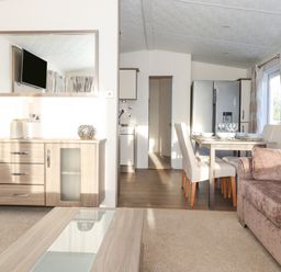 A living room with a sofa table and dining area with a refrigerator at Ursa in Felmoor Park