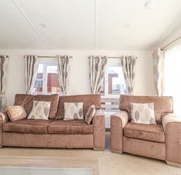 A living room with brown sofas and patterned curtains at Ursa in Felmoor Park