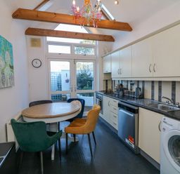 A kitchen with a round dining table and four chairs three have different colors and wall cabinets at 83 Upper John Street in Wexford Town County Wexford