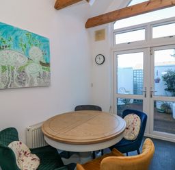 A dining area with a round wooden table and four colorful chairs next to glass doors leading to an outdoor patio at 83 Upper John Street in Wexford Town County Wexford