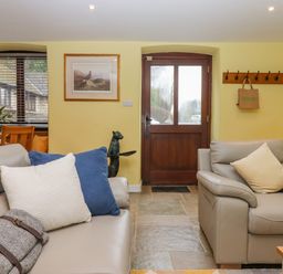 A living room with two grey sofas with cushions a wooden door and a window with blinds at Bradley Stables in Withypool