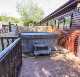 An outdoor deck area with a hot tub and two steps next to a wooden cabin at Ghyll Lodge Grasmere 25 White Cross Bay Windermere
