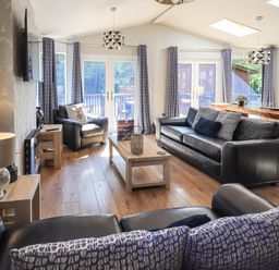 A living room with black leather sofas a wooden coffee table and armchairs at Ghyll Lodge Grasmere 25 White Cross Bay Windermere
