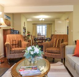 A living room with armchairs a coffee table a bouquet of flowers and a dining area in the background at Early Mist Cottage in Haytor Vale