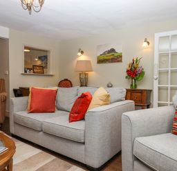 A living room with grey sofas and a striped armchair at Early Mist Cottage in Haytor Vale