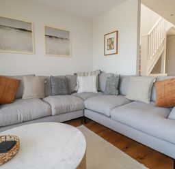 A corner sofa with cushions and framed pictures on the walls in a living room at 7 Longshore in St Columb Minor
