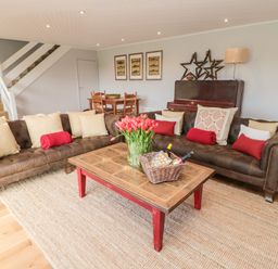 A living room with two brown sofas around a wooden coffee table with flowers and bottles at Whiteadder Bank in Berwick-Upon-Tweed