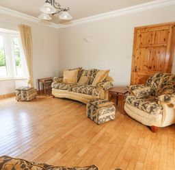 A living room with a patterned sofa armchair wooden door and window at Cloughoge House in Kilrush County Clare