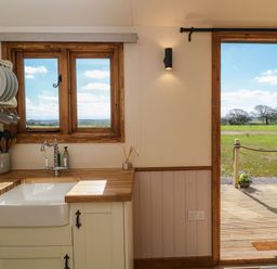 A kitchen sink area with wooden counters and a window overlooking a field at Buzzards in Morchard Bishop