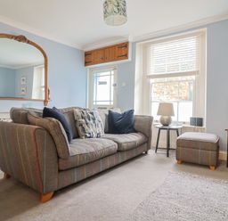 A living room with a sofa and a mirror at Riverdance Cottage in Lyme Regis